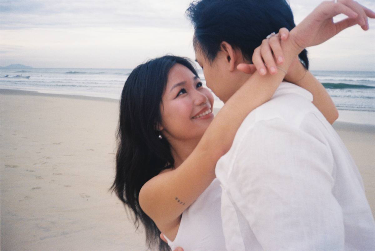 Tina smiling up at William in an embrace on the beach