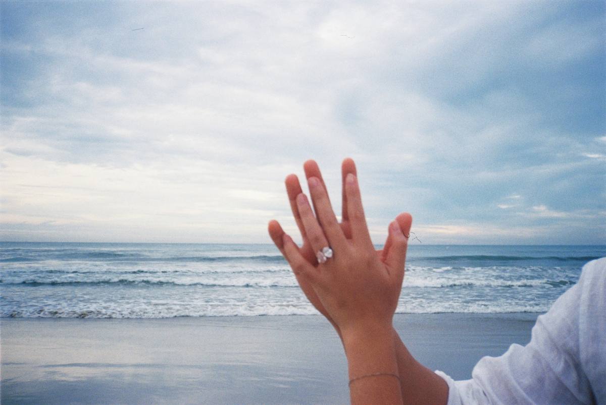 Tina's hand with her engagement ring against the sea